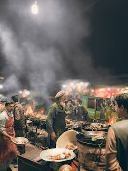 A lively scene of men cooking delicious street food amidst smoke at night in Peshawar.