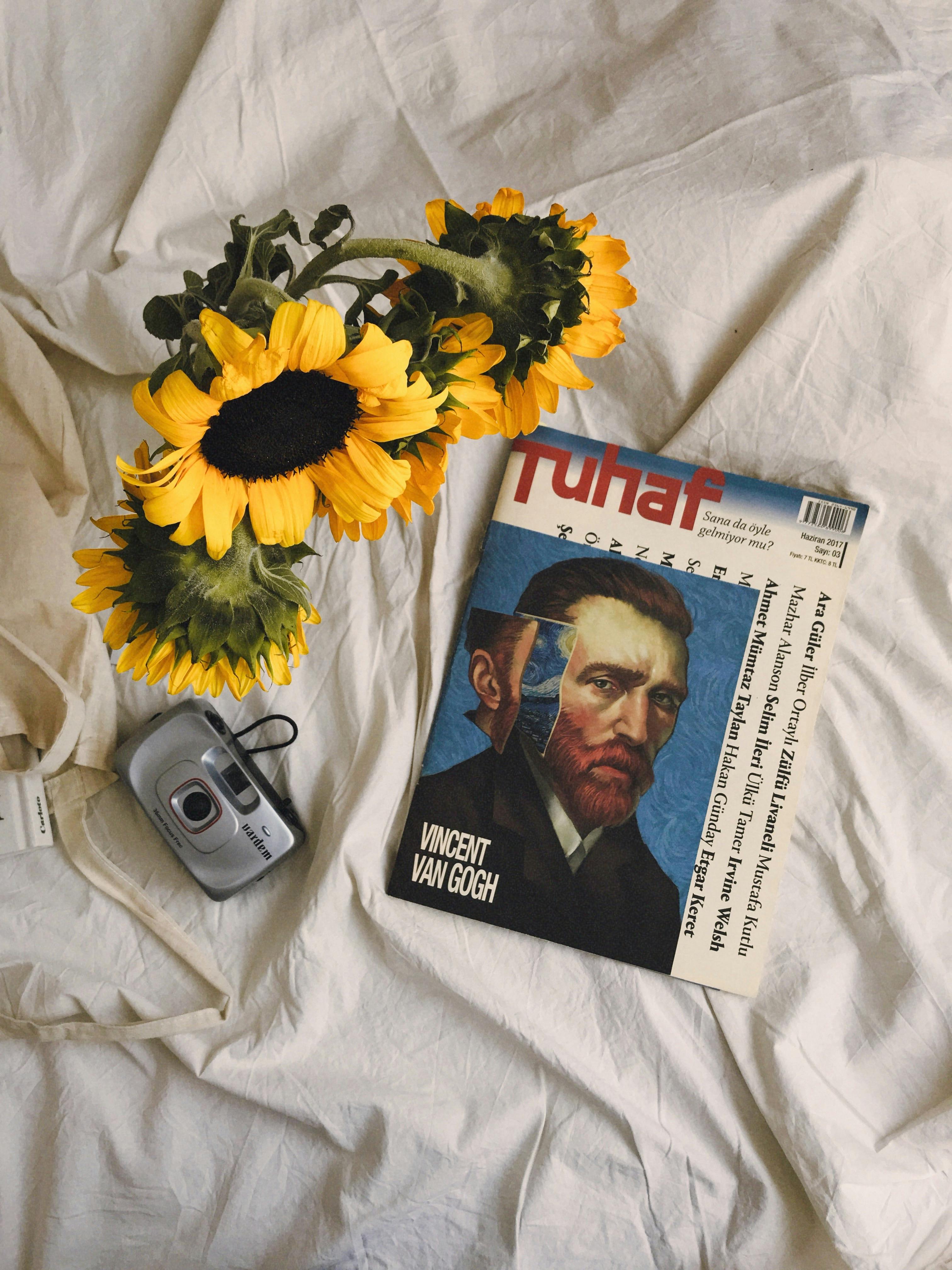 Artistic still life of sunflowers and magazine with Vincent Van Gogh portrait.