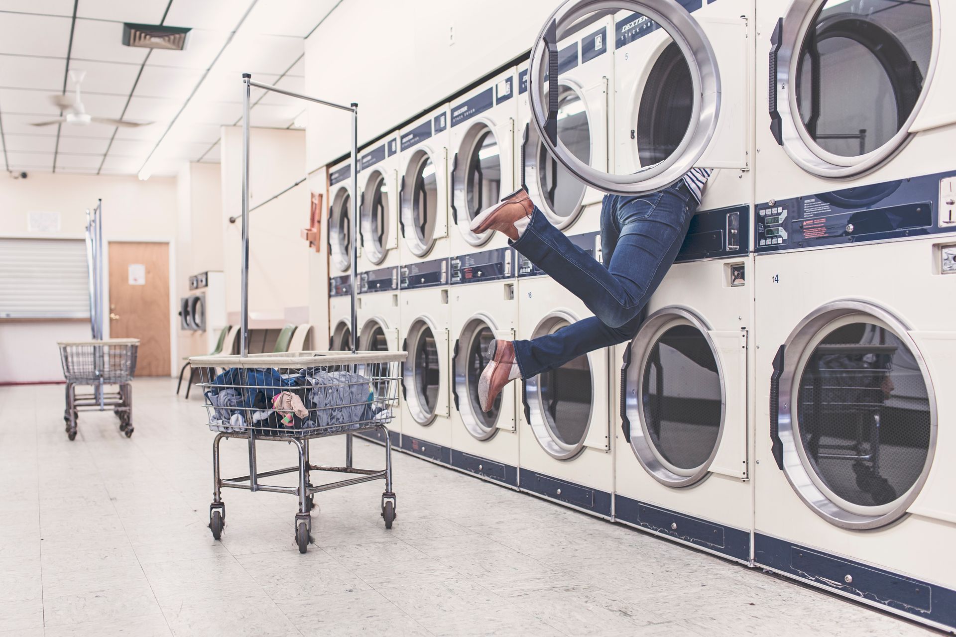 A funny scene in a laundromat with a person partially inside a dryer, highlighting everyday mishaps.