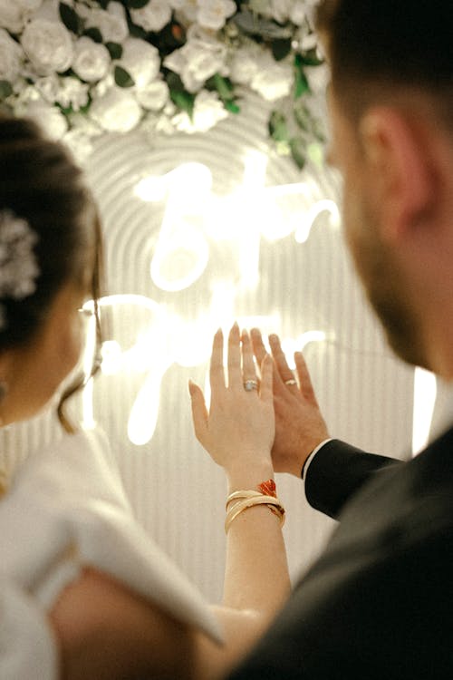 A bride and groom are holding hands in front of a sign