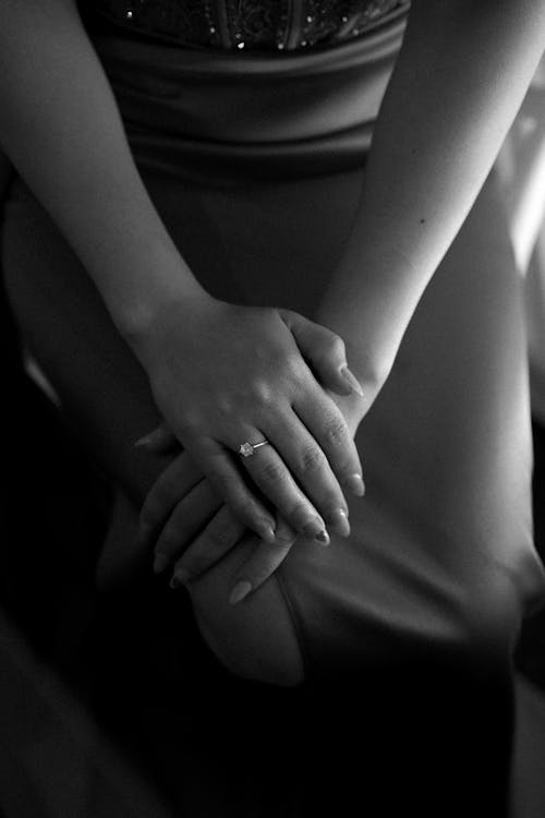 A black and white photo of a woman's hand holding her wedding ring