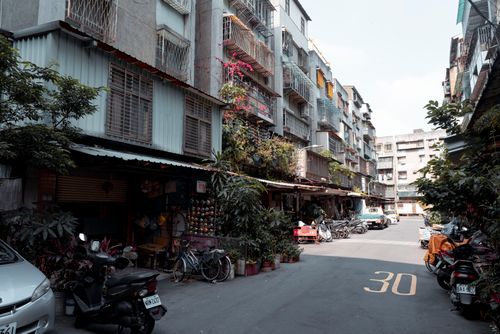Free Narrow urban alley with residential buildings, parked bicycles, and scooters. Stock Photo