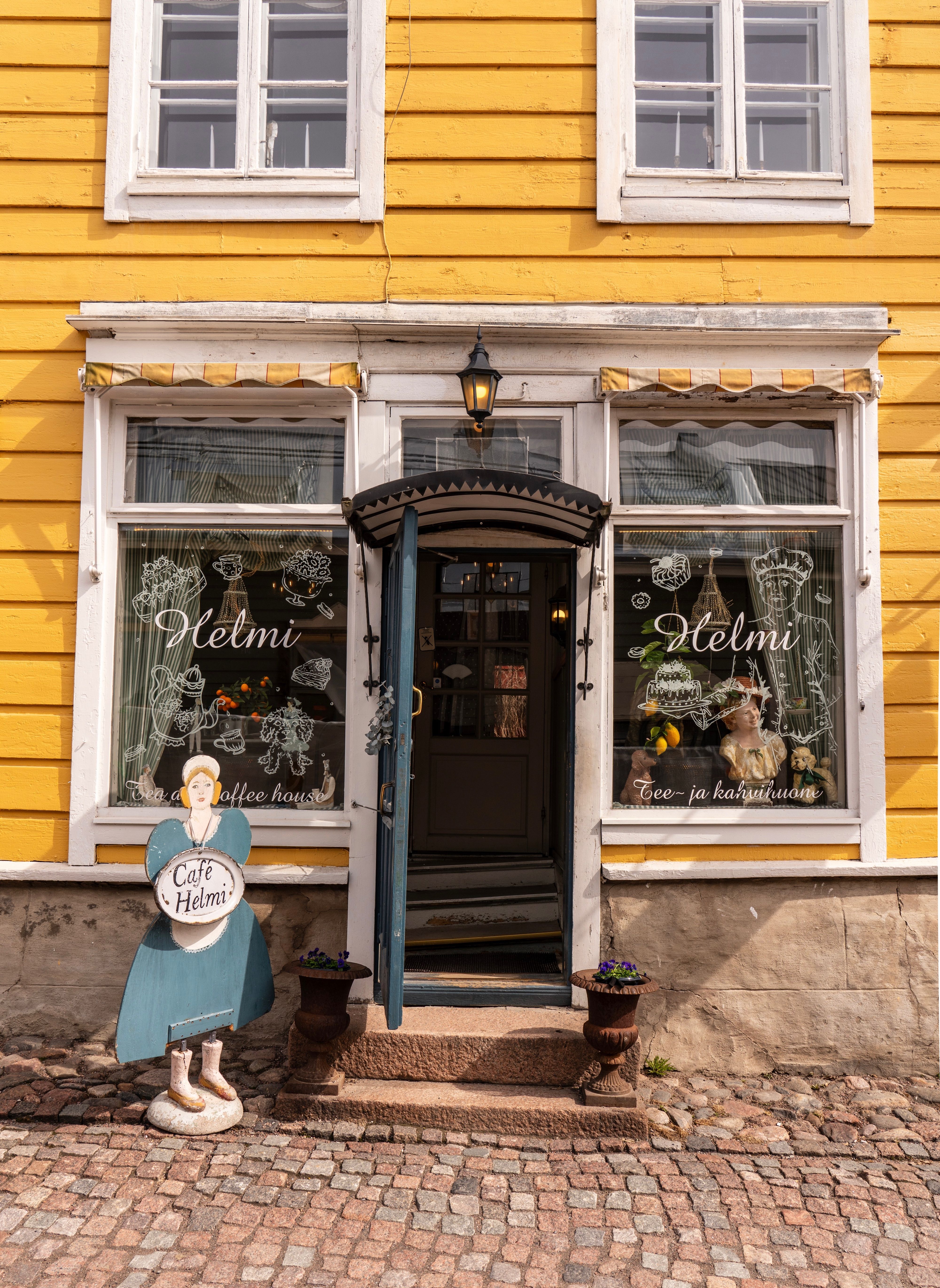 Inviting entrance of Café Helmi, showcasing a charming European street scene in Porvoo, Finland.