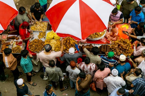 A crowd of people standing under an umbrella