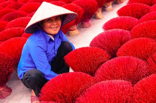 Free Asian woman crafting red incense bundles, showcasing traditional culture and craftsmanship. Stock Photo