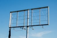 晴朗的蓝天下，空荡荡的金属广告牌框架矗立着，凸显了户外广告的基础设施