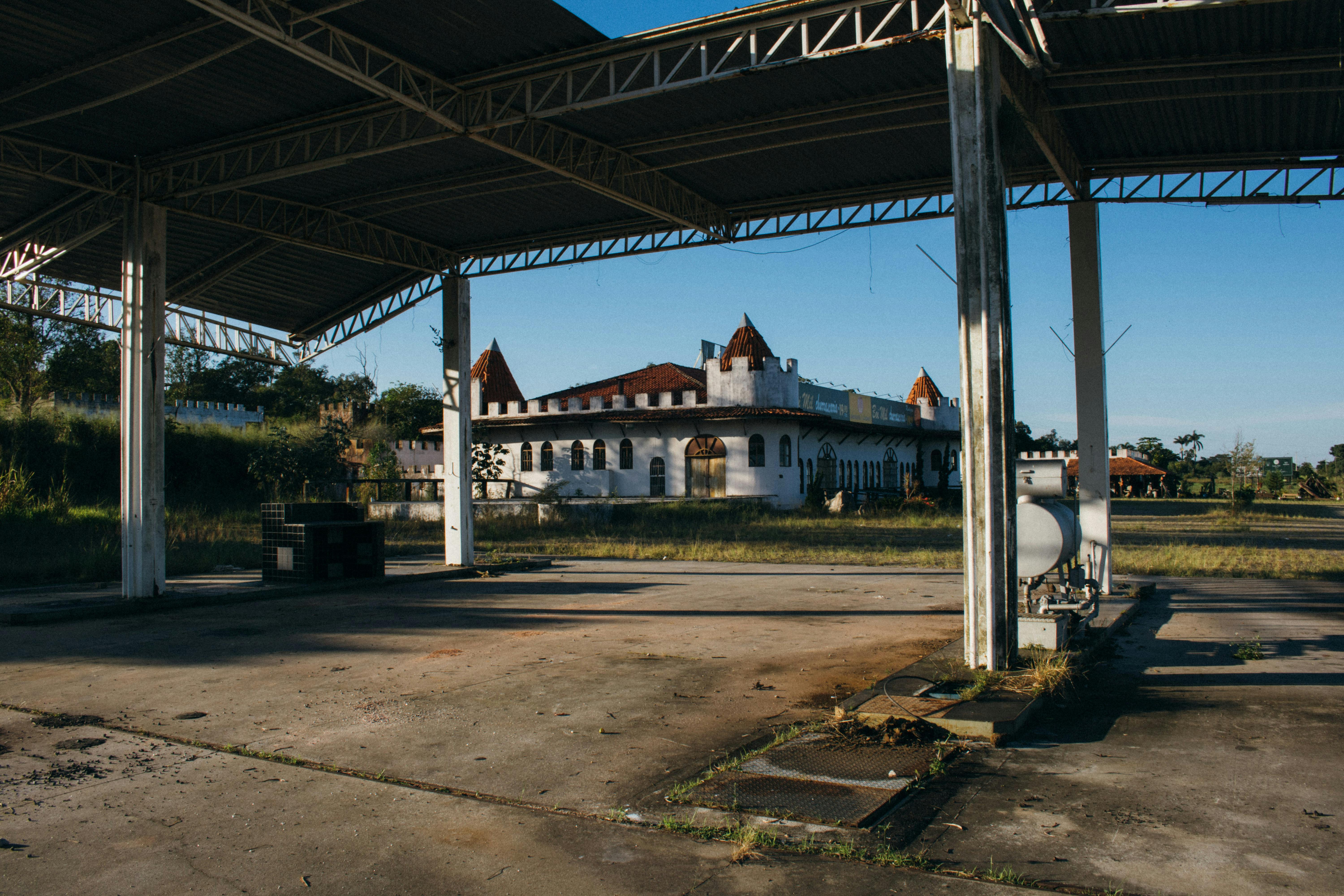 日落时分，透过金属结构能看到一座红色屋顶的废弃建筑