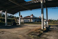 日落时分，透过金属结构能看到一座红色屋顶的废弃建筑