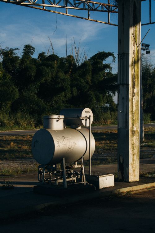 Free A metal fuel tank outdoors, highlighted by the warm sunset glow, surrounded by trees. Stock Photo