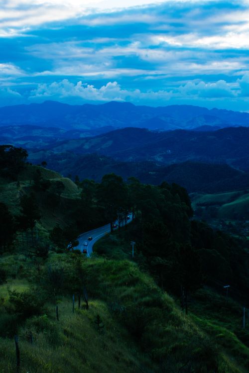 Free A stunning view of a winding mountain road at dawn surrounded by lush landscapes and mist. Stock Photo