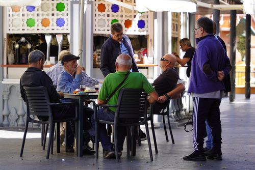 Free Group of elderly men socializing at an outdoor cafe, enjoying drinks and conversation. Stock Photo