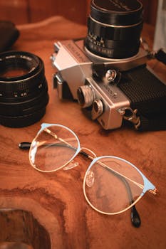 木制桌面上摆放着老式相机和眼镜，氛围温暖