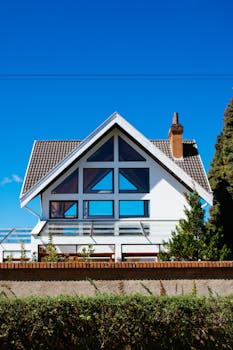 A modern A-frame house with large windows against a clear blue sky, showcasing contemporary architecture.