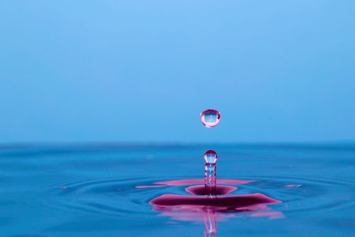 Free A vivid photo of a water droplet creating ripples on a colorful surface. Stock Photo