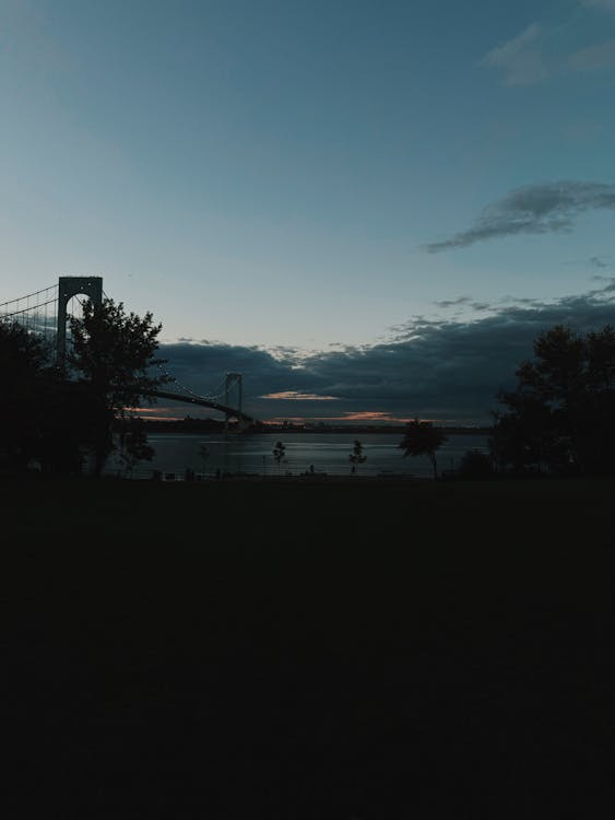 A bridge is seen at dusk with a sunset
