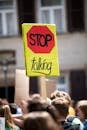 Woman in Black Shirt Holding Yellow and Black No Smoking Sign