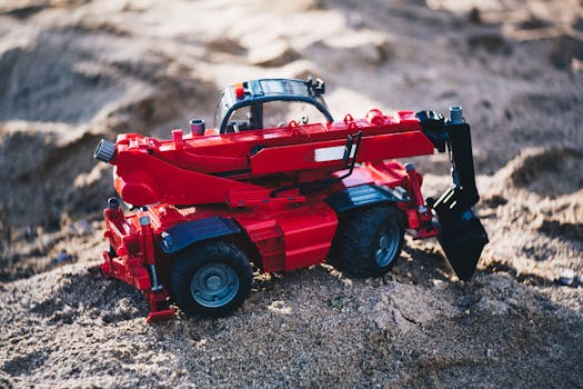 特写镜头捕捉了沙滩上红色玩具挖掘机的细节与色彩对比