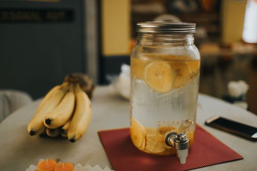 Free Citrus-infused water in a mason jar with bananas on a cozy kitchen table. Stock Photo