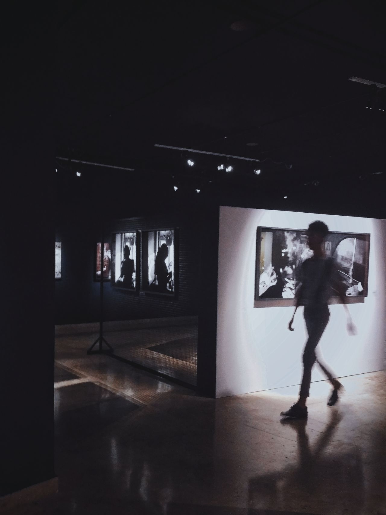 Dimly lit gallery hallway with framed photographs on the wall