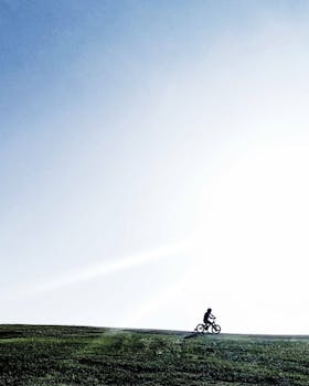 Silhouette of a cyclist biking over a hill under a clear sky in Minas Gerais, Brazil.