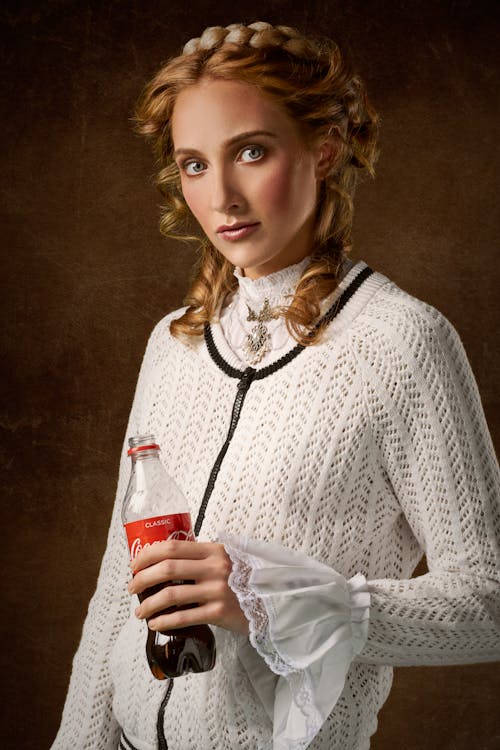 Femme Debout Portant Une Chemise à Manches Longues Blanche Tenant Une Bouteille De Coca Cola