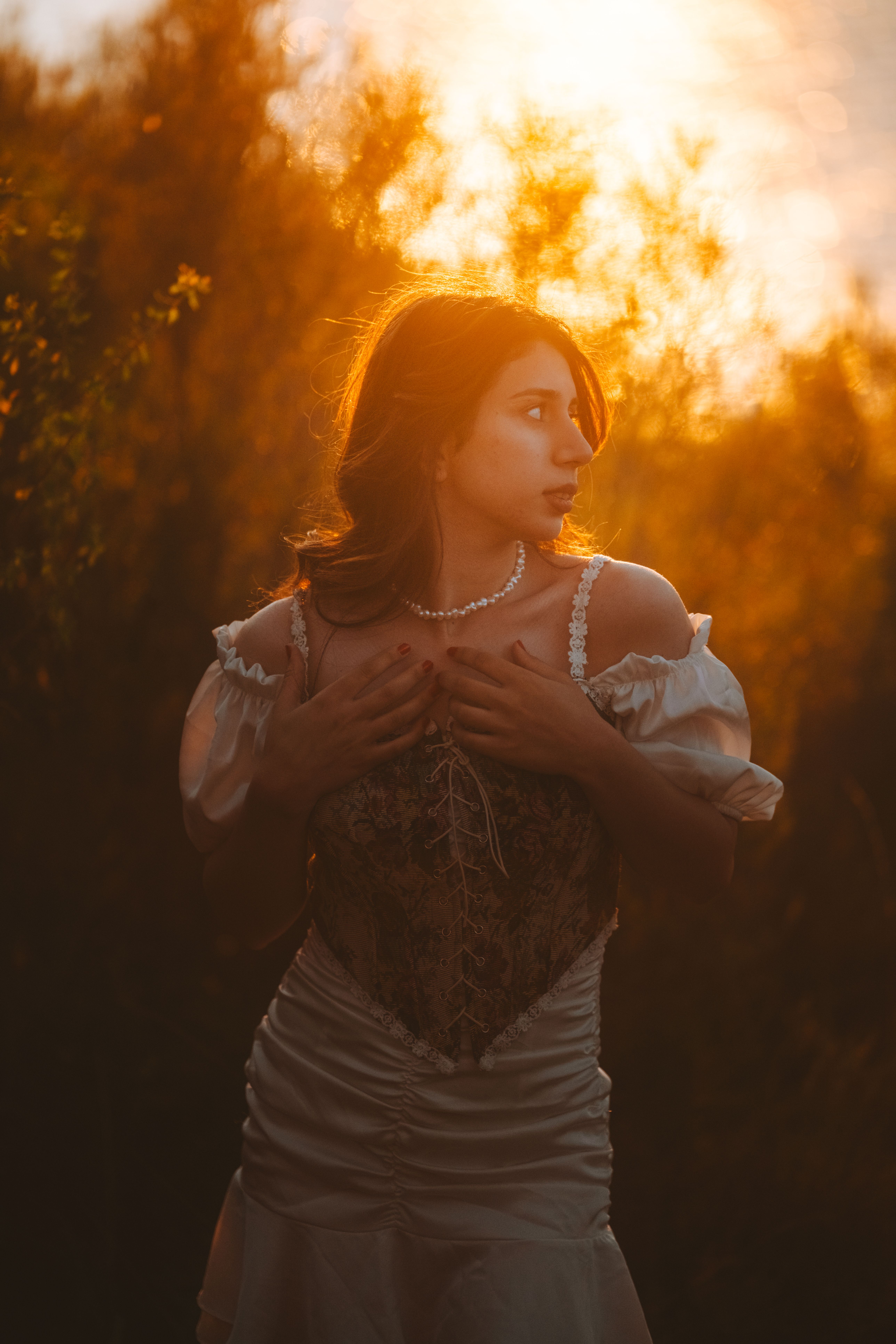 A woman in a vintage dress captured during sunset with a warm golden glow.