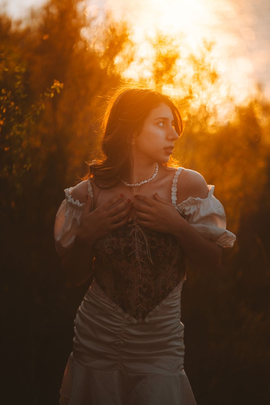 A woman in a vintage dress captured during sunset with a warm golden glow.