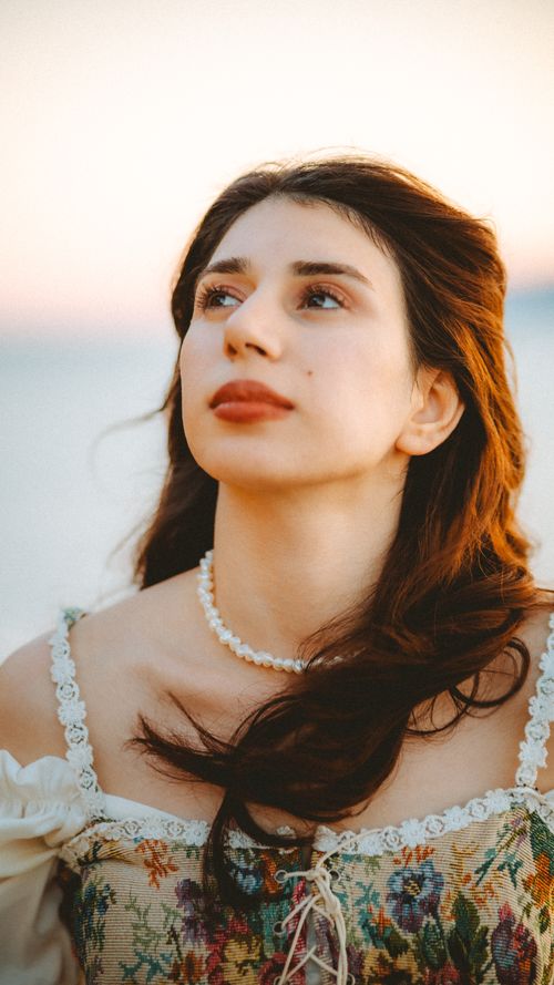 Free Soft-lit portrait of a brunette woman looking up, captured outdoors during sunset with a gentle breeze. Stock Photo