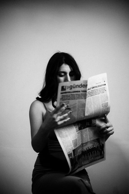 Free A brunette woman sitting and reading a newspaper in a black and white portrait. Stock Photo