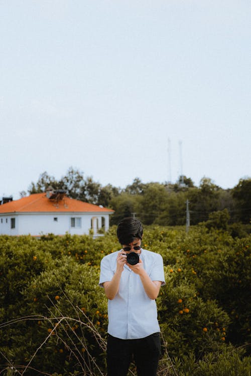 A man taking a photo of a house in the middle of a field