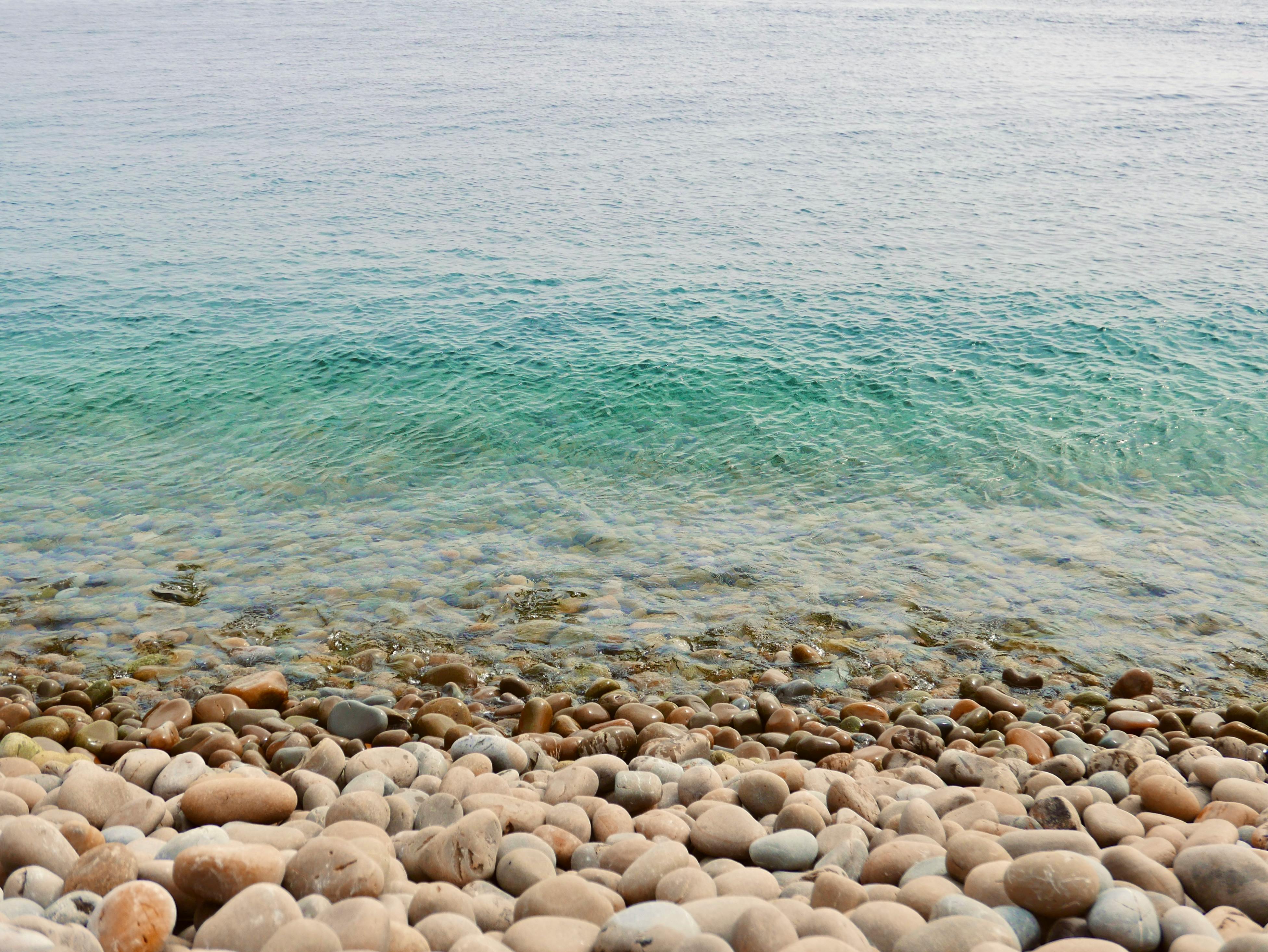 Tranquil pebble beach and clear sea at El Jebha, Morocco, featuring rippling waves.