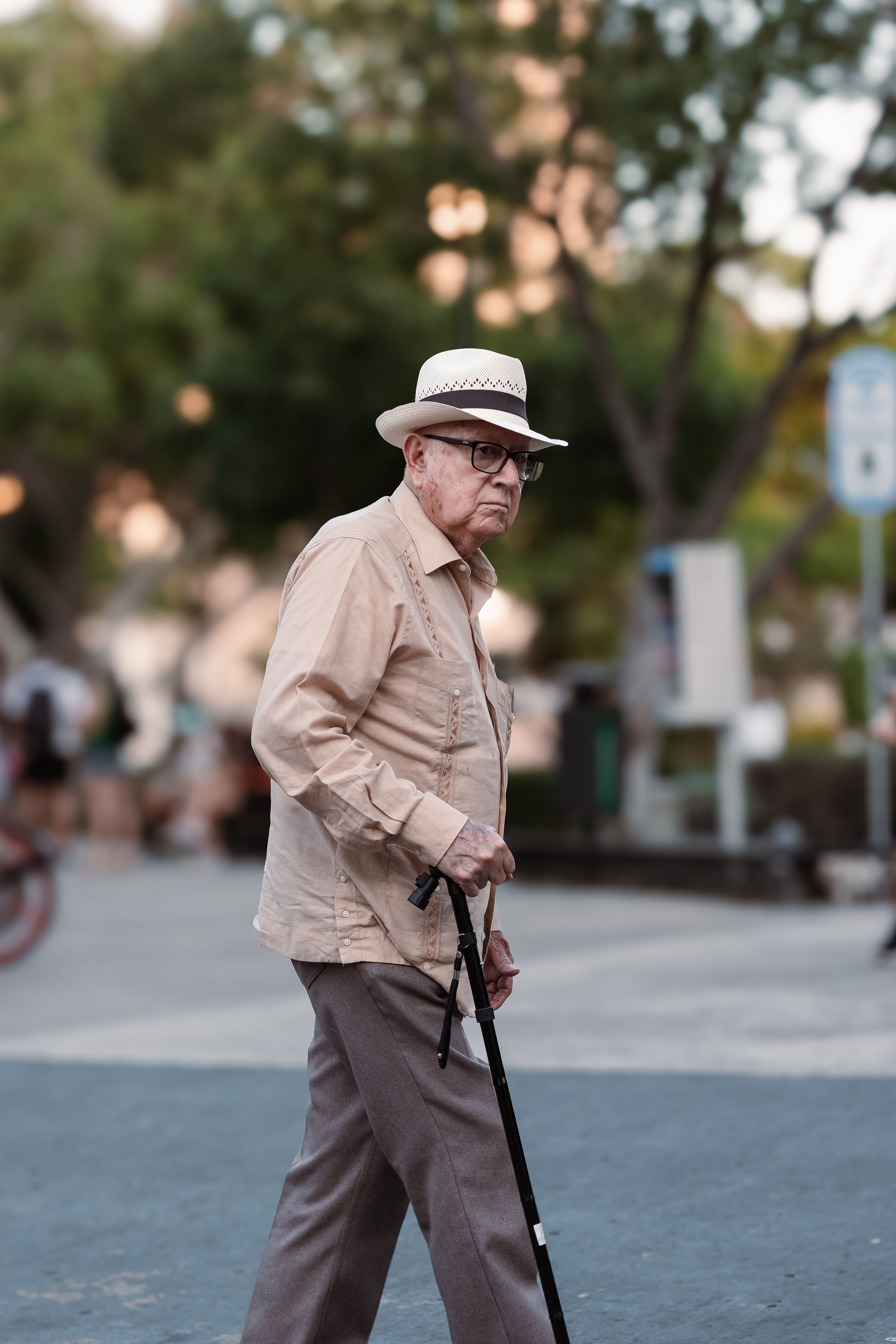 An older man walking with a cane on the street · Free Stock Photo