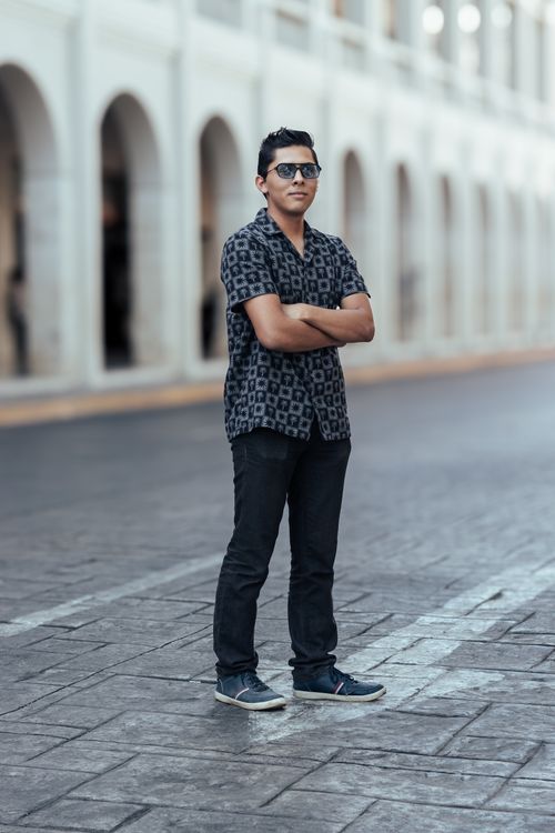 Free Young man in sunglasses and patterned shirt poses confidently on a city street, exuding style. Stock Photo