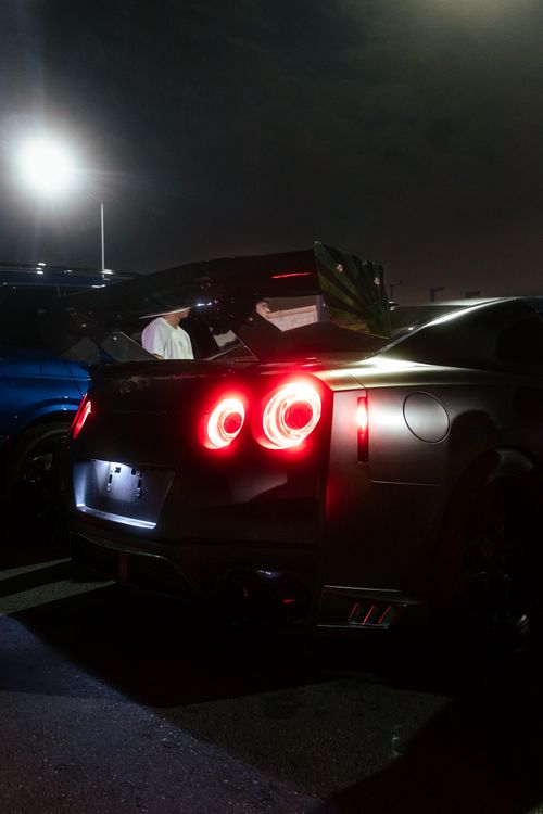 Free A sleek car with glowing taillights parked under a streetlight at night. Stock Photo