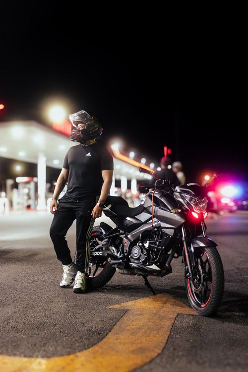 Free A motorcyclist stands with a motorcycle at night on city streets, exuding a cool urban vibe. Stock Photo