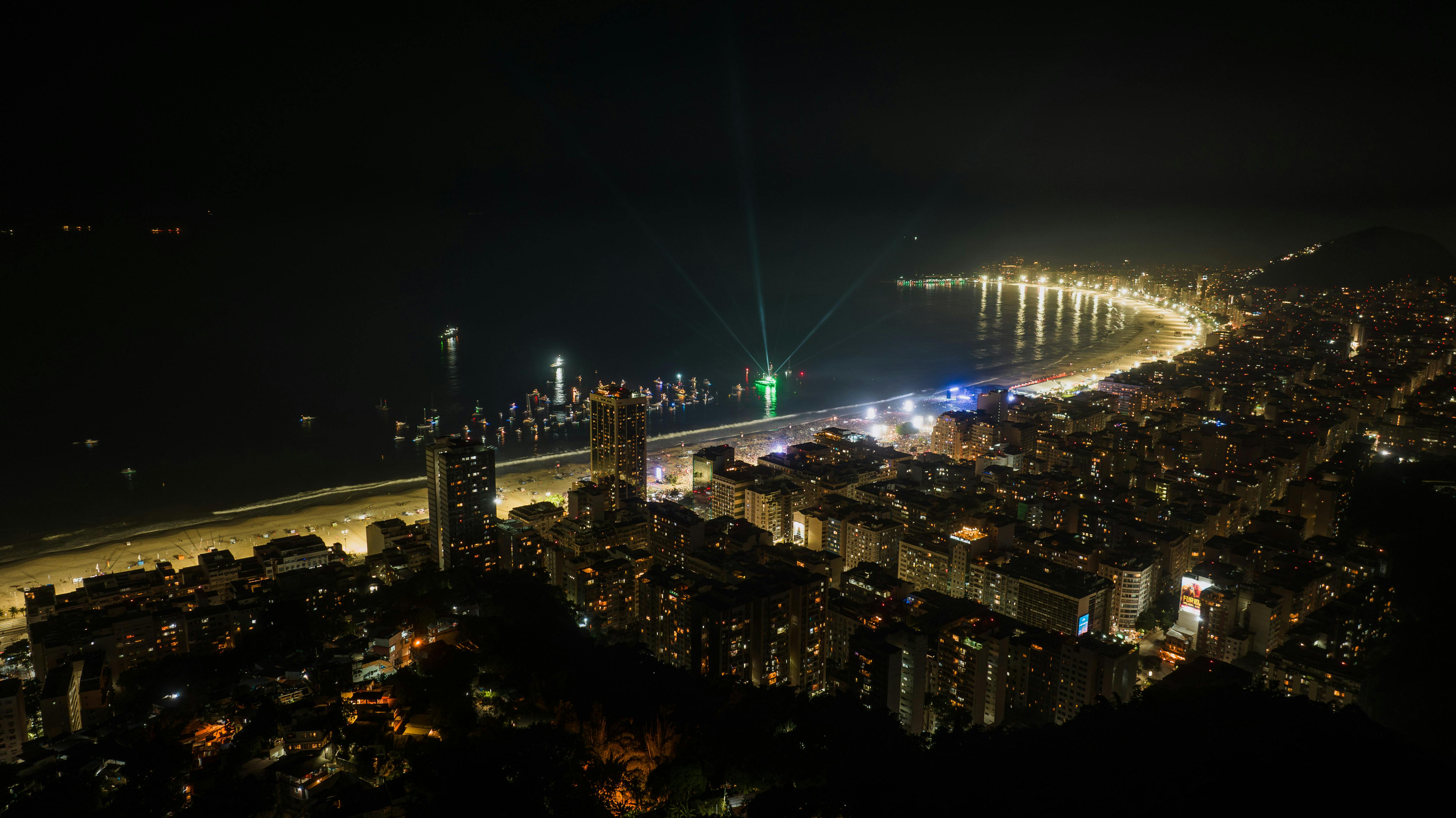 A breathtaking aerial night view of Rio de Janeiro's illuminated coastline, featuring vibrant city lights and the expansive sea.