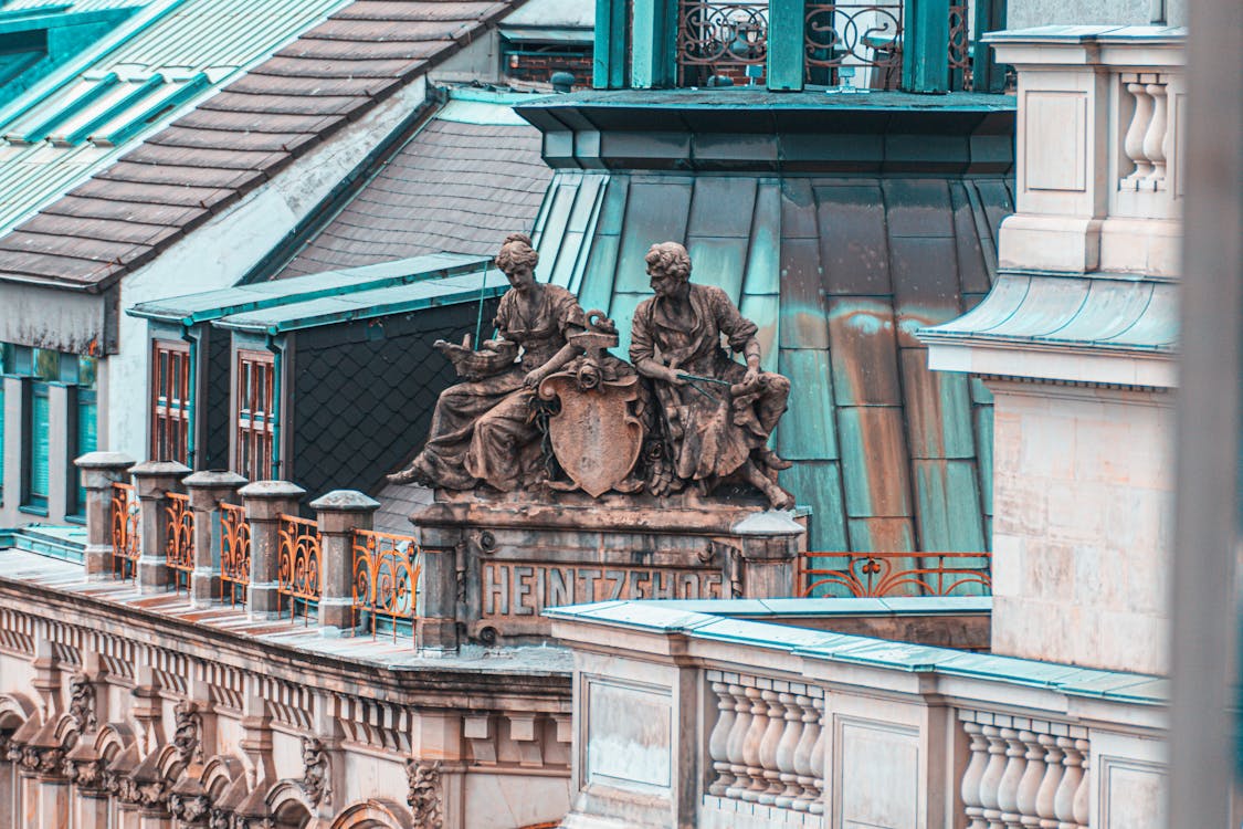 Photography of Two Person Statue Above on Building