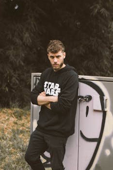 一位穿着星球大战连帽衫的年轻人在户外涂鸦前严肃地摆姿势