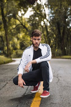 白天，年轻人穿着运动装蹲在荒无人烟的森林道路上