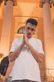 晚上，一个年轻人站在古典建筑的大柱子前