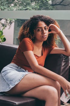 一个年轻女子在室内真皮沙发上放松的休闲肖像，她留着卷发