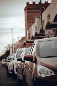 City street featuring parked cars with urban buildings in the background, showcasing traffic and city life.