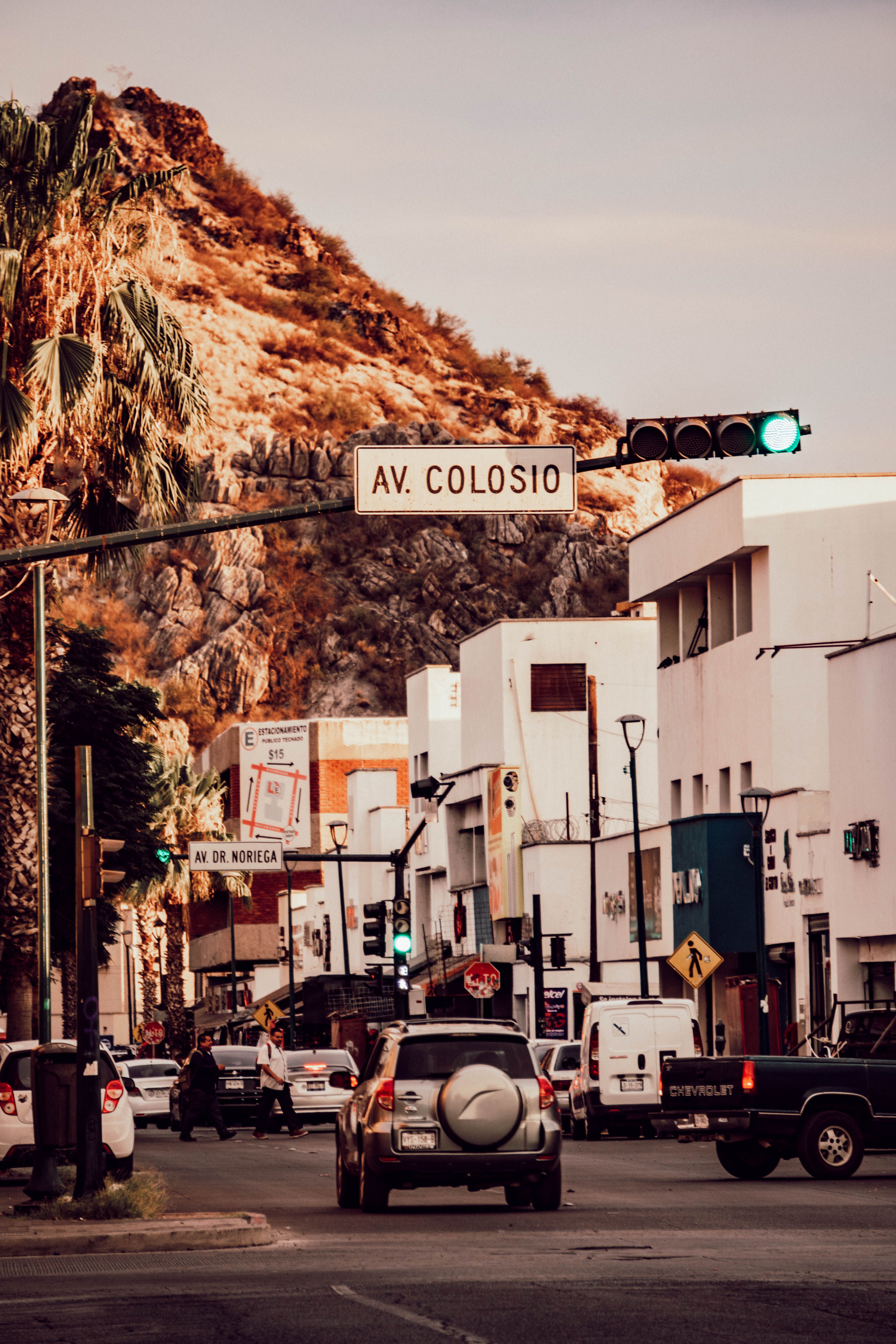 Busy urban street in a Mexican city with vehicles and buildings under a green traffic light.