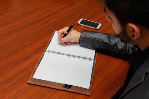 Man Writing on Notebook