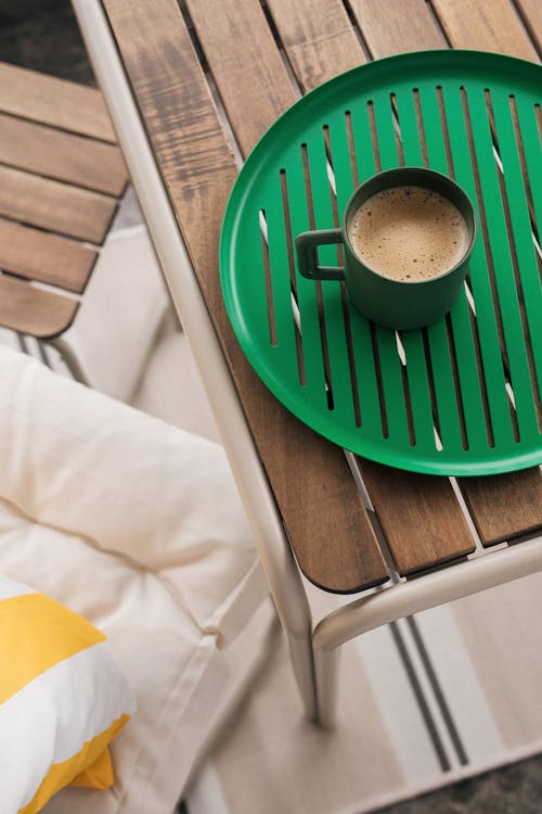 A green tray with a cup of coffee on it