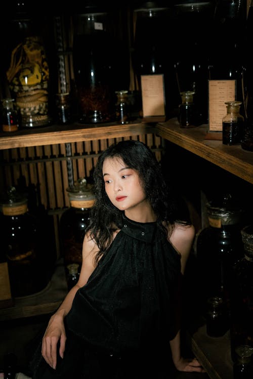 A girl in black sitting in a room with shelves