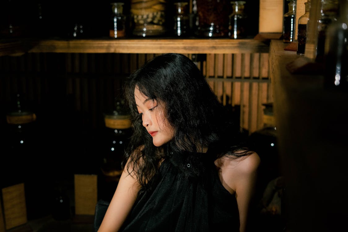 A woman in black dress sitting on a wooden bench