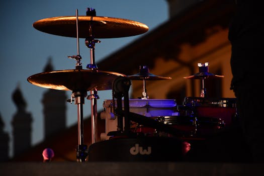 A drum kit setup on stage at twilight, highlighting cymbals and hardware.