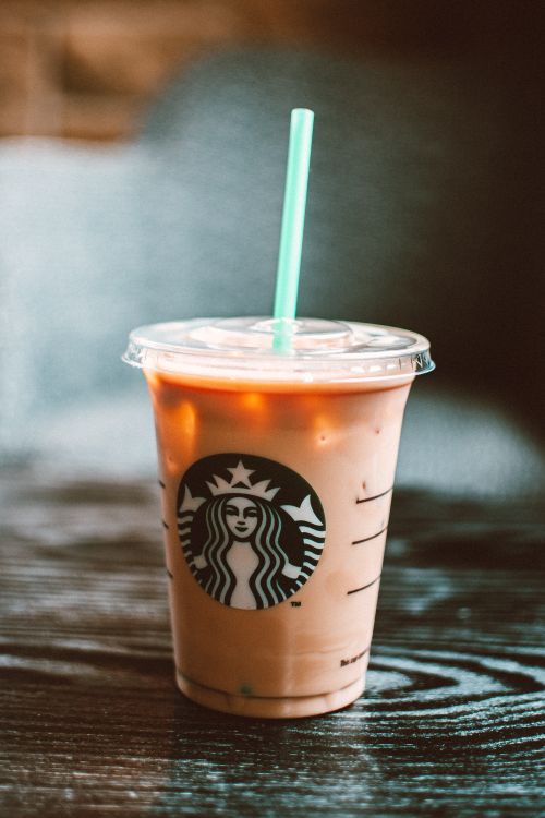 Free Chilled iced coffee in a Starbucks cup on a wooden table creating a refreshing vibe. Stock Photo