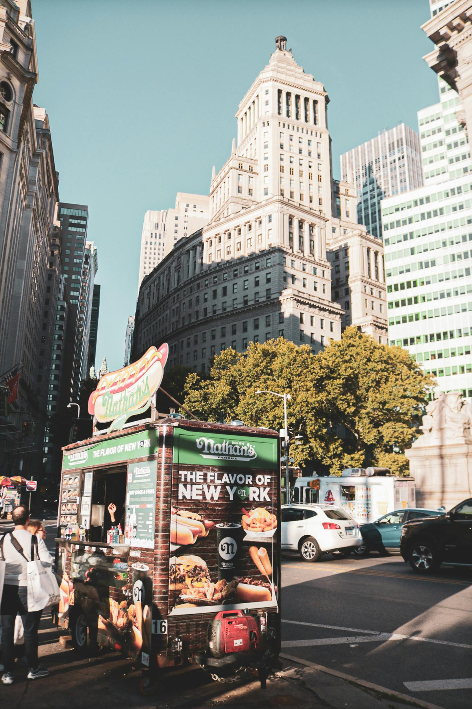 Vibrant street scene in New York City featuring a classic food cart and historic architecture.